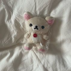 a white teddy bear wrapped in plastic on a bed