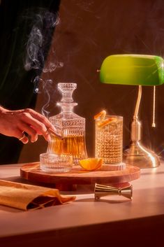 a person is pouring tea into a decanter on a wooden tray with an orange slice