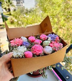 a box filled with pink and purple cupcakes sitting on top of a table