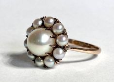 "Beautiful antique natural pearl cluster ring in 10K yellow gold from the Victorian era. The lovely ring features eleven sea pearls, held firmly in place within a decorative antique claw mount setting. The top of the ring measures 13.8mm diameter, with the center pearl at 7.4mm and the outer pearls at 3.2mm each. The pearls and setting are in excellent condition. Beautiful solid luster on all pearls. Ring size 6 1/4 and easily sized up or down several sizes.  Please allow one week for sizing. One month layaway payment plans for items $500 and over available.  Approximate Age - Victorian Gemstone(s) - natural sea pearl, 8.5mm Metal - 14K yellow gold Weight - 3 grams Ring size - 6 1/4 Marks -  Makers Mark - Comments -  Service & Sizing Information: If you require ring sizing or service, kind Pearls Ring, Pearl Cluster Ring, Antique Engagement Rings Vintage, Opal Band, Poetry Images, Victorian Rings, Pearl Cluster, Antique Engagement Rings, Natural Pearl