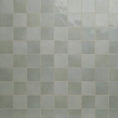 a white toilet sitting next to a tiled wall