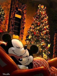 a mickey mouse sitting on top of a couch next to a christmas tree with lights