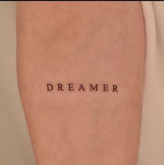 a woman's arm with the word dream written on it in cursive font