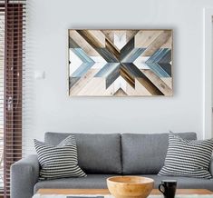 a living room with a gray couch and wooden wall art on the wall above it