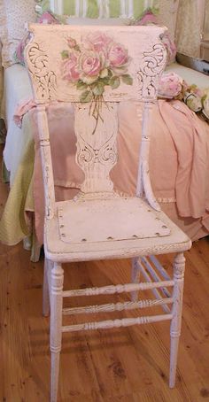 a white chair sitting on top of a hard wood floor next to a pink bed