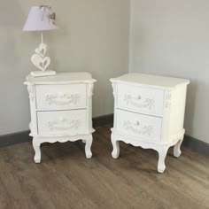 two white nightstands sitting next to each other on a wooden floor