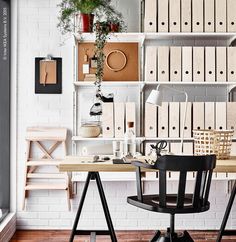 a desk and chair in front of a white wall with lots of boxes on it