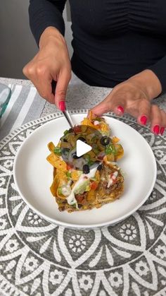 a woman is cutting into a piece of food on a plate with a knife and fork