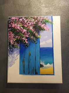 a painting of pink flowers on a blue door by the beach with waves in the background