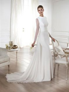 a woman in a white wedding dress standing next to a chair