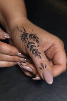 a woman's hand with a tattoo on her left thumb and fingers, holding the other