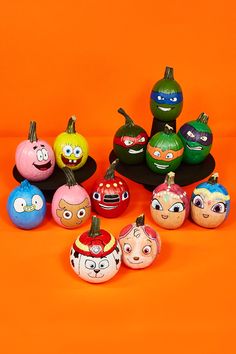 a group of painted pumpkins sitting on top of an orange surface with faces drawn on them