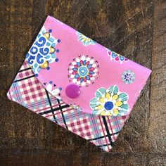 a pink wallet sitting on top of a wooden table next to a purple and blue flower