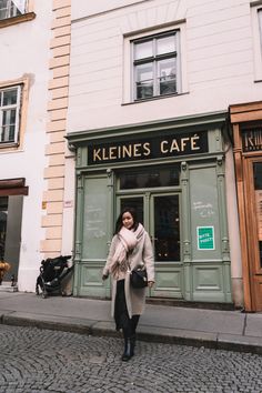 a woman walking down the street in front of a cafe