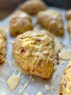 biscuits with icing and cranberries sitting on top of a piece of parchment paper