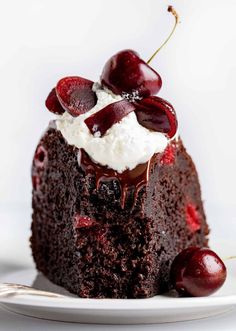 a piece of chocolate cake topped with whipped cream and cherries