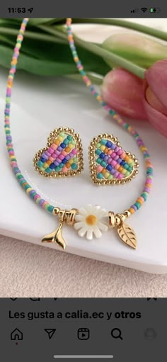 a necklace and earring set with flowers on the side, sitting next to a flower