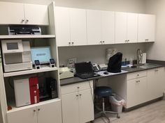 an office with white cabinets and black counter tops, including a computer on the desk