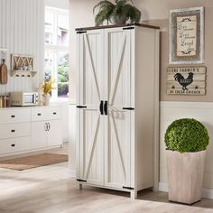 a large white cabinet in a kitchen next to a potted plant on the floor