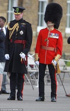 two men in uniform standing next to each other on the street with people looking at them