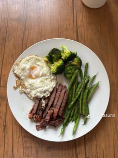 a white plate topped with steak, broccoli and eggs