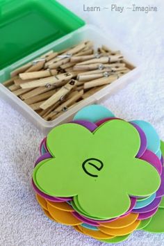 a bunch of wooden pegs sitting on top of a table next to a plastic container