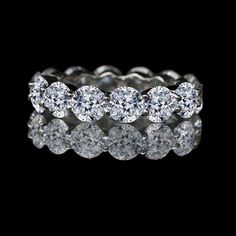 a white gold ring with five round diamonds on the top and bottom, set in 18k white gold