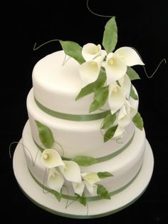 a wedding cake with white flowers and green leaves