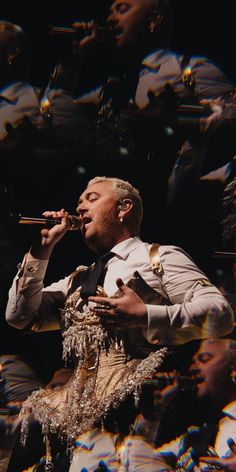 a man in uniform singing into a microphone while surrounded by other men and women on stage