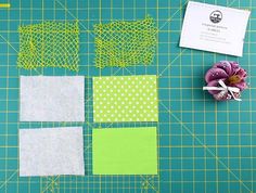 some green and white pieces of fabric on a cutting board with a flower in the middle