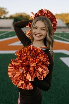 a girl in black and orange uniform holding a cheerleader's pom - pom