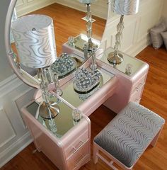 a pink vanity table with two lamps and a mirror