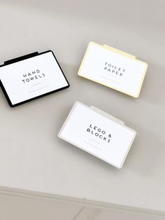 three small business cards sitting on top of a white table next to a black and yellow box