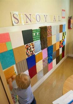 a little boy standing in front of a colorful wall