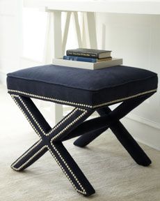 a black stool with two books on top of it next to a white table and chair