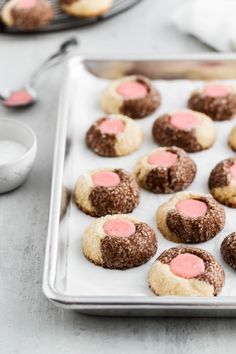 cookies with pink frosting are on a baking sheet