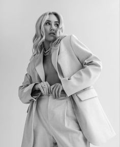 a woman in a white suit posing for a black and white photo with her hands on her hips