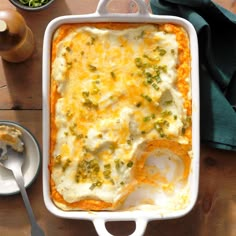 a casserole dish with cheese and broccoli in it on a wooden table