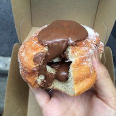 a half eaten chocolate covered doughnut in a box