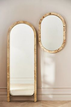 an oval mirror next to a wall with a wooden frame and two mirrors on it