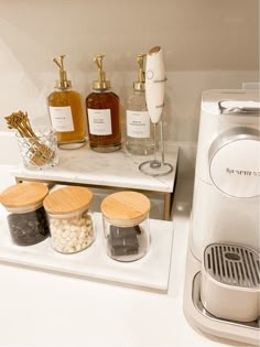 the coffee maker is sitting on top of the counter next to some bottles and spices