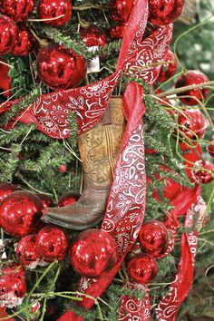 a christmas tree decorated with red ornaments and cowboy boot ornament hanging from it