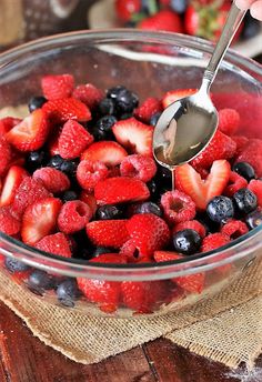 a bowl full of berries and strawberries with a spoon in it