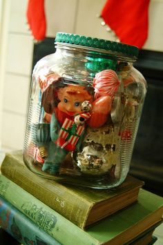 a glass jar filled with christmas decorations sitting on top of books