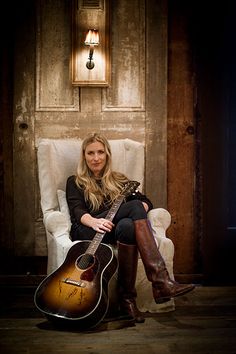 a woman sitting in a chair holding a guitar