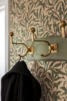 coat rack with hooks on wall next to green and white wallpapered wall paper