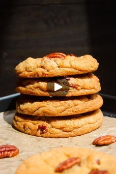 three cookies stacked on top of each other with pecans scattered around them and the cookie being cut in half