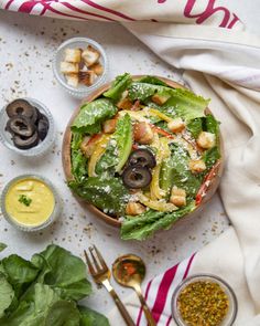 a salad with olives, lettuce and other ingredients on a white surface