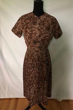 I am offering a 1950s cotton voile sun dress and jacket ensemble. This set is in a brown floral print. The sleeveless dress has a square neckline on the fitted bodice The skirt is narrow pleats. It has a narrow zipper and back zipper. The jacket is short and fitted with a Peter Pan collar. It buttons up the front. Measurements: Jacket Bust 36 in. Waist 26 in. Length 15 in. Dress Bust 34-36 in. Waist 26 in. Hips 36 in. With some wiggle room due to pleats Length 42 in. Spring Brown Floral Print Sundress, Vintage Brown Printed Dress, Vintage Brown Collared Dress, Vintage Brown Floral Print Dress, Retro Brown Floral Print Dress, Brown Floral Print, Dress And Jacket, Sun Dress, Brown Floral