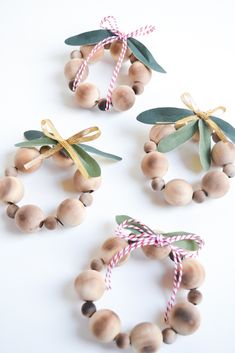 three wooden beads tied with twine and green leaves on white background, set of 3